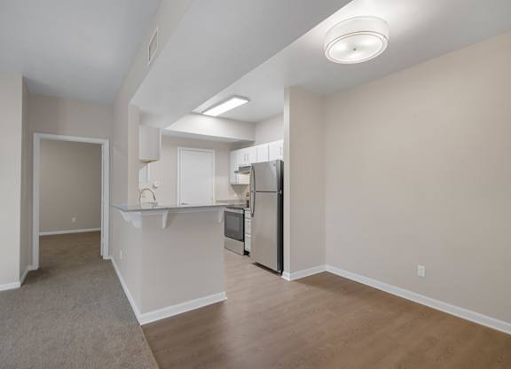 A kitchen area with a refrigerator, sink, and cabinets.