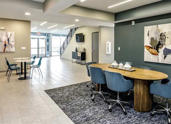 A modern dining room with a round wooden table and blue chairs.