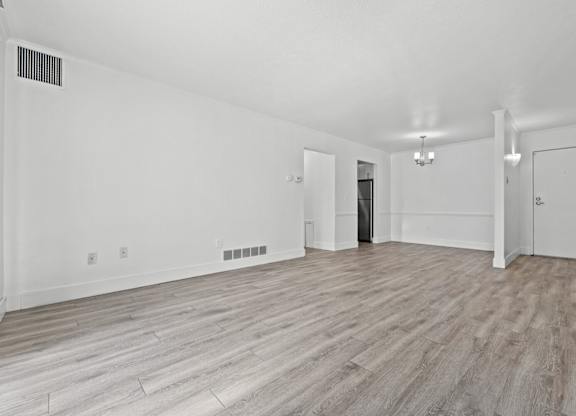 A spacious room with wood flooring and white walls.