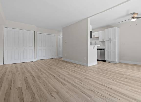 an empty living room with wood flooring and a kitchen at Sunnymede Apartments - Troy, MI, Troy, Michigan