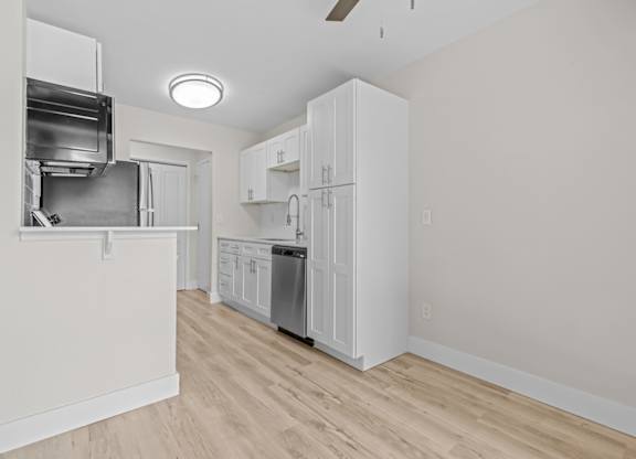 a renovated kitchen with white cabinets and a stainless steel refrigerator at Sunnymede Apartments - Troy, MI, Troy