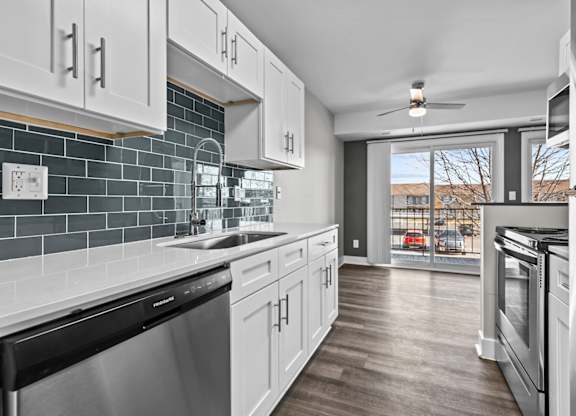a kitchen with white cabinets and stainless steel appliances and a window at Sunnymede Apartments - Troy, MI, Troy, 48084