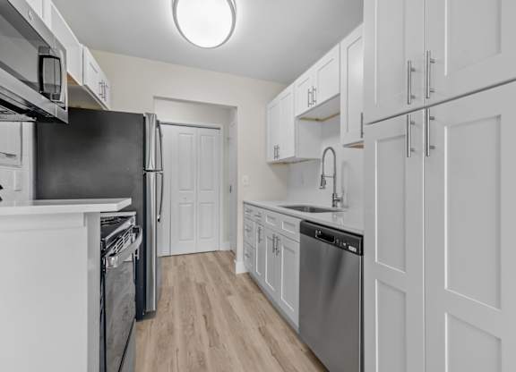 a white kitchen with stainless steel appliances and white cabinets at Sunnymede Apartments - Troy, MI, Michigan, 48084