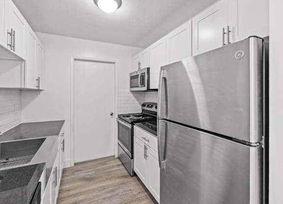 A modern kitchen with a stainless steel refrigerator and a microwave above the stove.