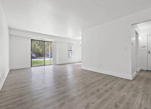 A spacious room with wooden flooring and white walls.