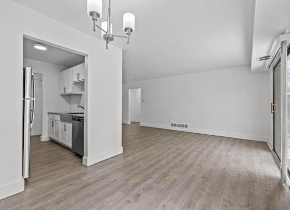 A spacious kitchen with white cabinets and a refrigerator is visible.