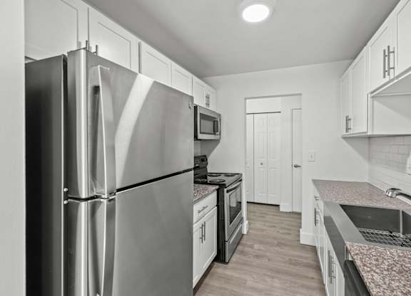 A modern kitchen with a stainless steel refrigerator and granite countertops.
