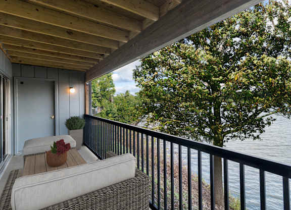 A balcony with a couch and a view of the water at The Waverly on the Lake - Belleville, MI Apartment, Belleville, MI, 48111