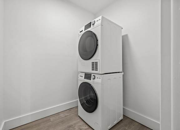 Two white front loading washing machines in a white room.