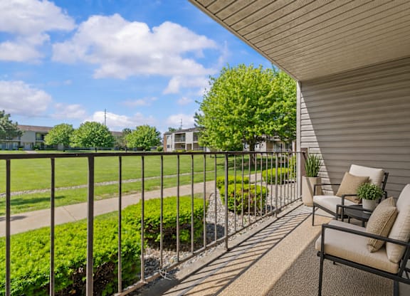 A balcony with a metal railing, a chair, and a potted plant.