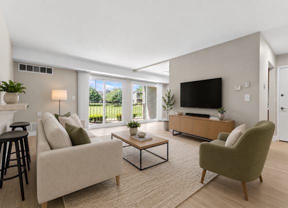 A modern living room with a beige sofa, a green armchair, and a wooden coffee table.