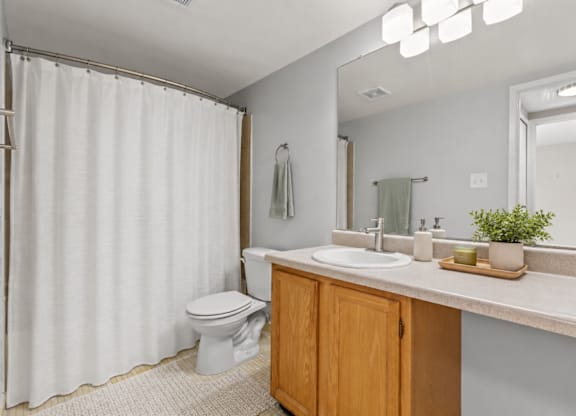 A white bathroom with a toilet, sink, and shower curtain.