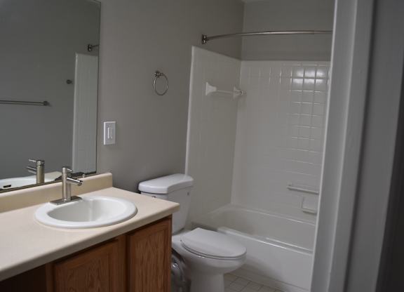 A white toilet sits next to a sink in a bathroom at Sunnymede Apartments in Troy, MI