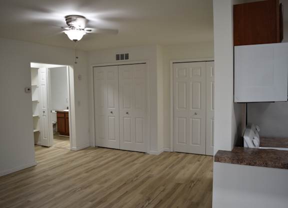 A room with white walls and wooden floors with a ceiling fan and a window at Sunnymede Apartments in Troy, MI