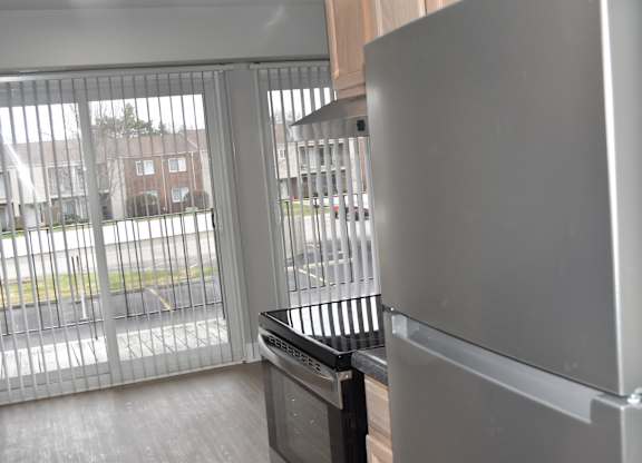 A modern kitchen with a stainless steel refrigerator and a dishwasher at Sunnymede Apartments in Troy, MI