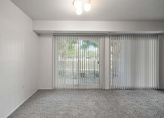 an empty living room with white walls and sliding glass doors at Sunnymede Apartments - Troy, MI, Troy, MI, 48084