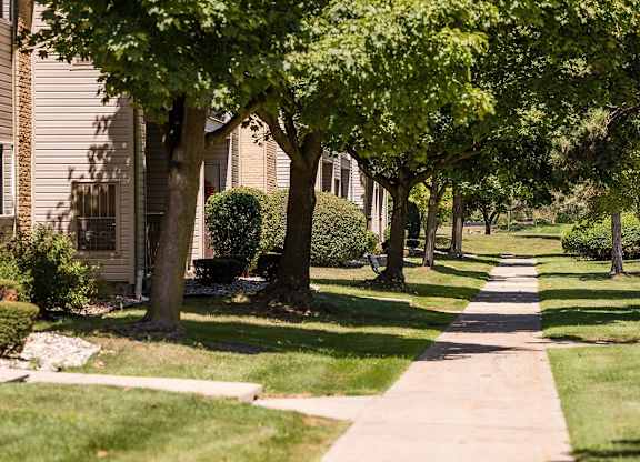 a tree lined sidewalk in front of a house at Sunnymede Apartments - Troy, MI, Troy, Michigan