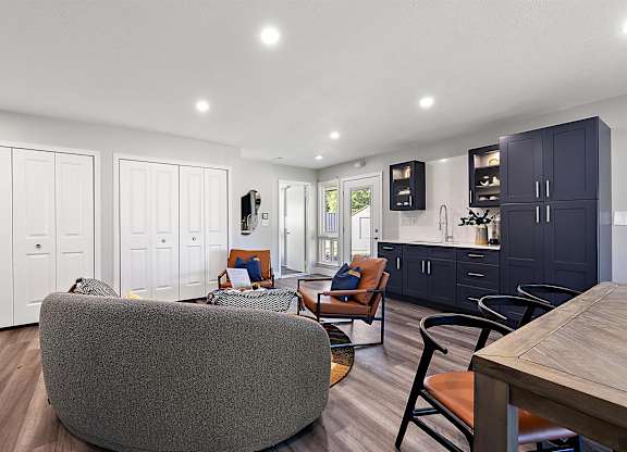 a living room with a kitchen and a table and chairs at Sunnymede Apartments - Troy, MI, Troy, 48084