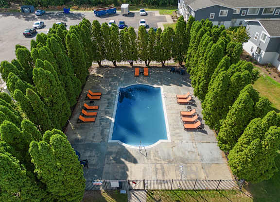 an aerial view of a swimming pool surrounded by trees at Town & Country Apartments - Wixom, MI, Wixom, 48393