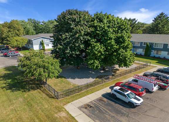 Aerial view of a parking lot with cars in front of a house at Town & Country Apartments - Wixom, MI, Michigan