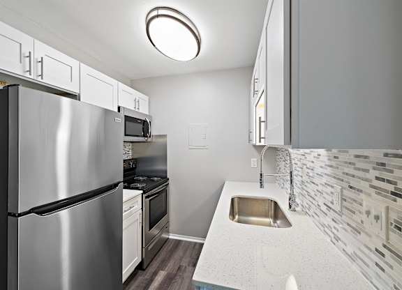 a kitchen with stainless steel appliances and white counter tops at Town & Country Apartments - Wixom, MI, Wixom, Michigan