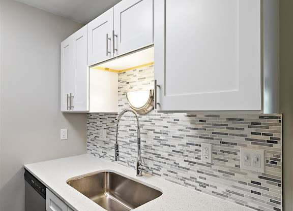 a kitchen with white cabinets and a sink at Town & Country Apartments - Wixom, MI, Wixom