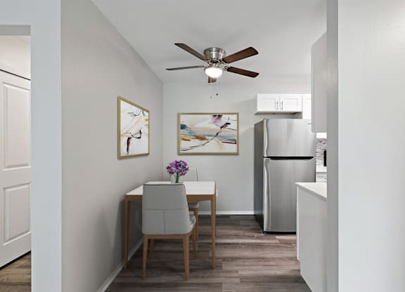 dining room with a table and chairs and a kitchen with a refrigerator at Town & Country Apartments - Wixom, MI, Wixom, 48393