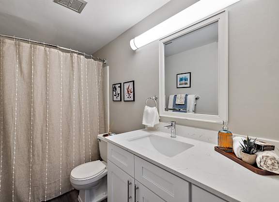 a bathroom with a white sink and toilet and a shower at Town & Country Apartments - Wixom, MI, Michigan