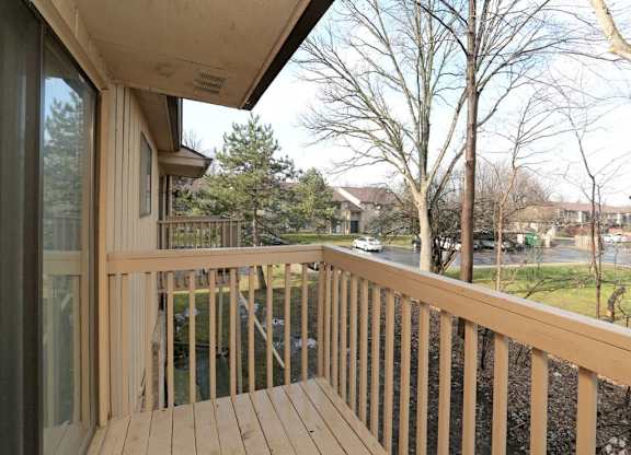 a balcony with a wooden railing and a street in the background
