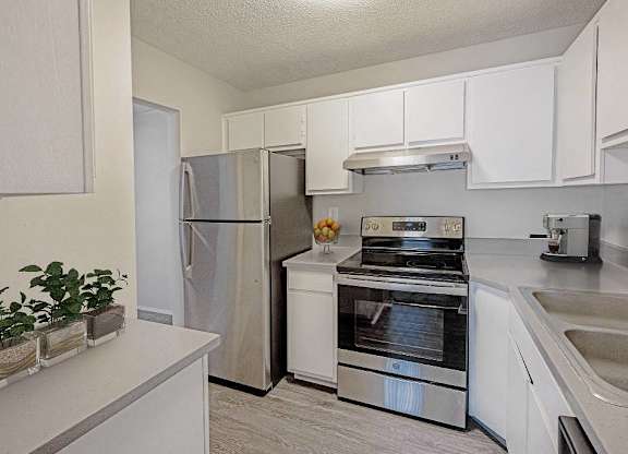 A kitchen with a stainless steel refrigerator, oven, and sink at The Waverly on the Lake - Belleville, MI Apartment , Belleville, Michigan