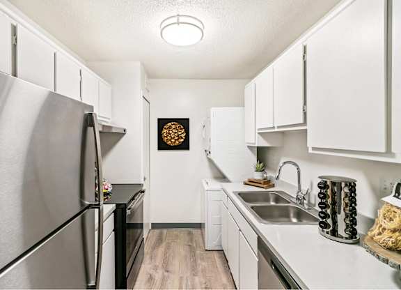 A kitchen with a stainless steel refrigerator and white cabinets at The Waverly on the Lake - Belleville, MI Apartment, Belleville, MI, 95050