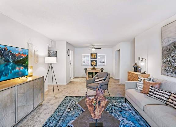 A living room with a couch, a chair, a coffee table, and a painting on the wall at The Waverly on the Lake - Belleville, MI Apartment , Michigan, 95050