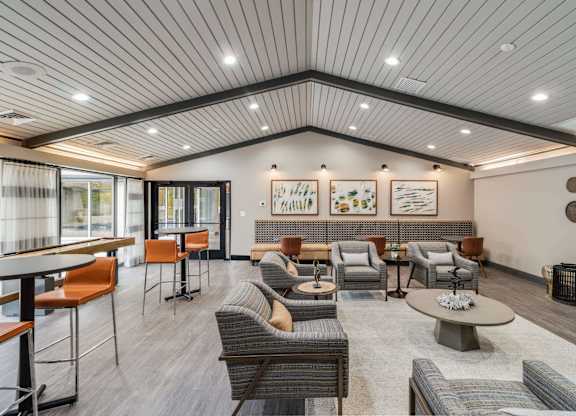 A spacious waiting area with a variety of seating options and artwork on the walls at The Waverly on the Lake - Belleville, MI Apartment , Michigan, 48111