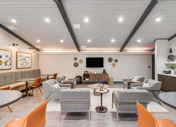 A modern living room with a grey sofa set, a coffee table, and a TV mounted on the wall at The Waverly on the Lake - Belleville, MI Apartment , Belleville