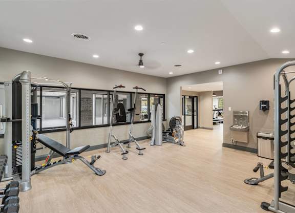 A spacious gym with a variety of equipment including treadmills, weights, and exercise machines at The Waverly on the Lake - Belleville, MI Apartment , Belleville, MI