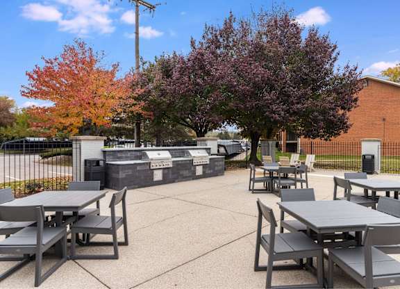 A park with tables and chairs surrounded by trees at The Waverly on the Lake - Belleville, MI Apartment , Michigan