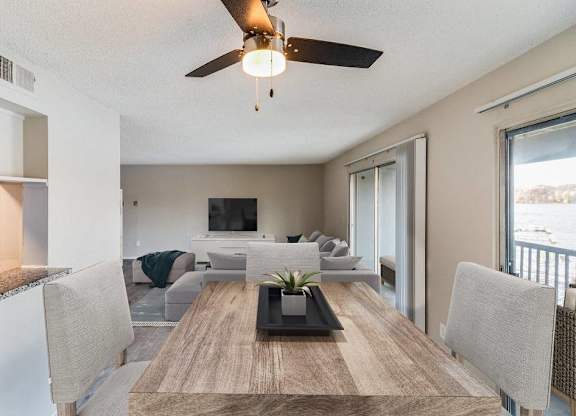 A modern dining room with a wooden table and grey chairs at The Waverly on the Lake - Belleville, MI Apartment , Belleville