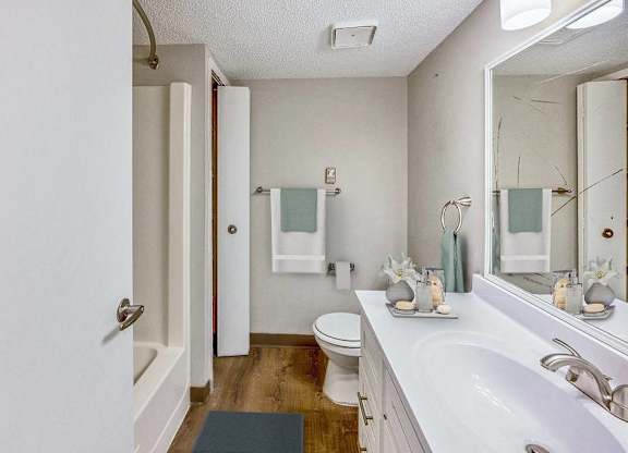 A white bathroom with a toilet, sink, and mirror at The Waverly on the Lake - Belleville, MI Apartment , Michigan