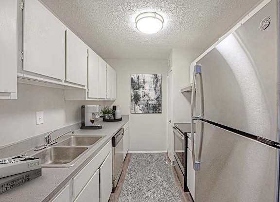 A kitchen with a sink, refrigerator, and cabinets at The Waverly on the Lake - Belleville, MI Apartment , Belleville, 48111