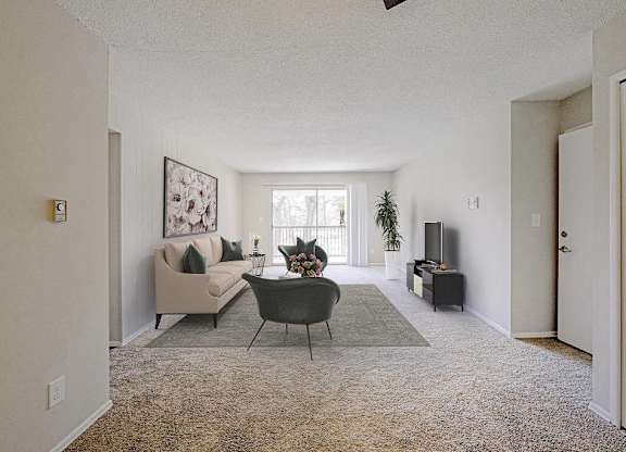A living room with a couch, chair, and potted plant at The Waverly on the Lake - Belleville, MI Apartment , Belleville, MI