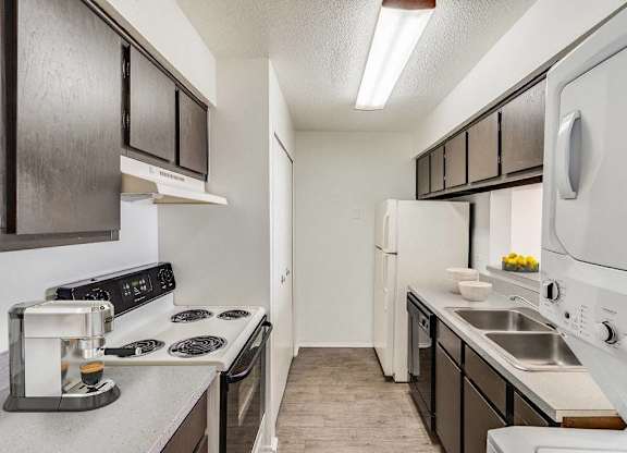A kitchen with black cabinets and white appliances at The Waverly on the Lake - Belleville, MI Apartment , Belleville