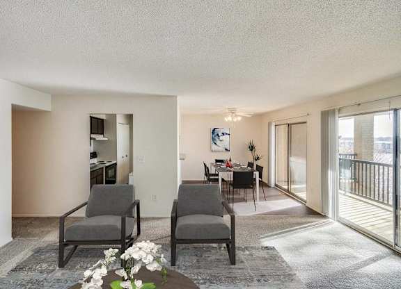 Two grey chairs are placed in a room with a table and a vase of flowers at The Waverly on the Lake - Belleville, MI Apartment , Belleville, Michigan