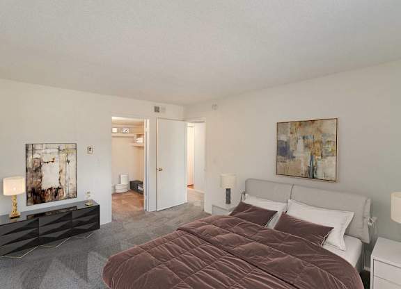 A bedroom with a large bed and a painting on the wall at The Waverly on the Lake - Belleville, MI Apartment , Belleville, Michigan