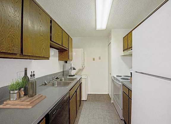A kitchen with wooden cabinets and a white refrigerator at The Waverly on the Lake - Belleville, MI Apartment , Belleville, Michigan