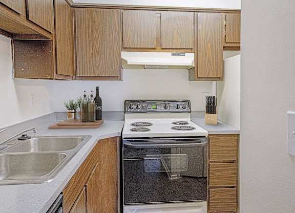A modern kitchen with wooden cabinets and stainless steel appliances at The Waverly on the Lake - Belleville, MI Apartment, Belleville, MI, 95050