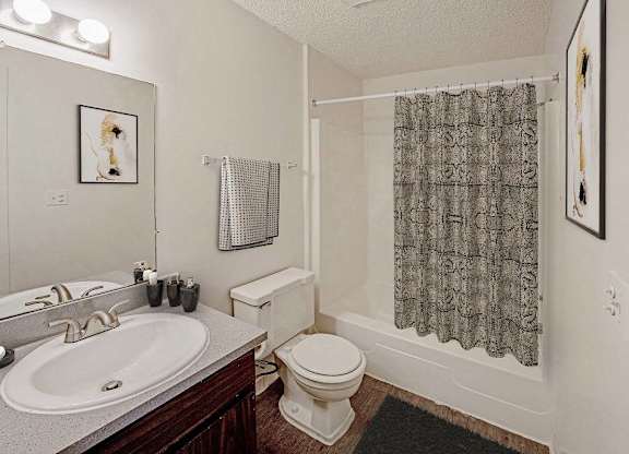 A bathroom with a toilet, sink, and shower curtain at The Waverly on the Lake - Belleville, MI Apartment , Belleville