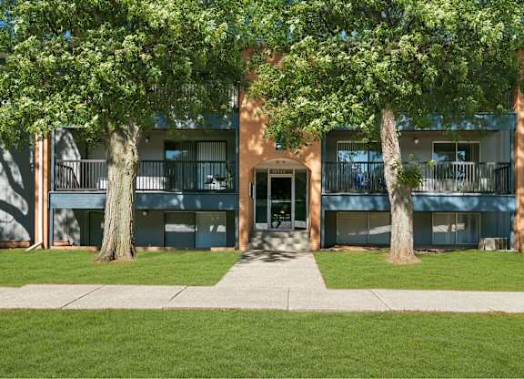 A building with a tree in front of it at The Waverly on the Lake - Belleville, MI Apartment , Belleville