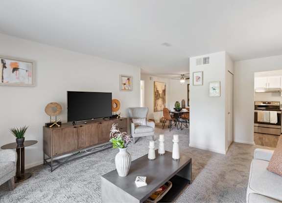 A modern living room with a grey carpet and a wooden entertainment center at The Waverly on the Lake - Belleville, MI Apartment , Michigan, 95050