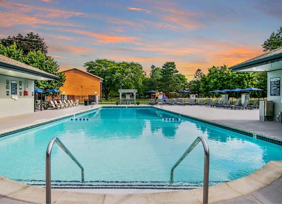 A large swimming pool with a metal ladder in the foreground at The Waverly on the Lake - Belleville, MI Apartment , Belleville, MI