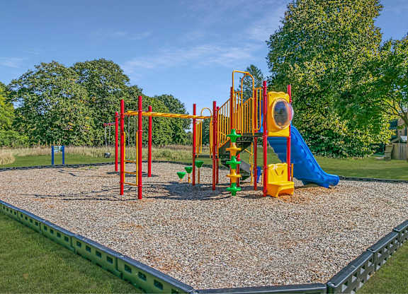 A playground with a yellow slide and a green slide at The Waverly on the Lake - Belleville, MI Apartment , Michigan, 95050